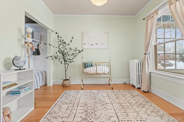 living area with crown molding, radiator heating unit, hardwood / wood-style floors, and plenty of natural light