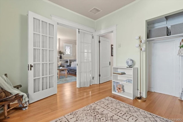 interior space with hardwood / wood-style flooring, crown molding, and french doors