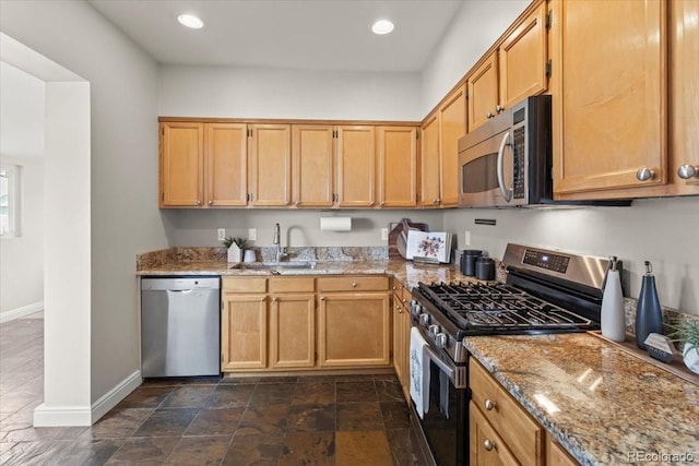 kitchen with light stone countertops, appliances with stainless steel finishes, and sink