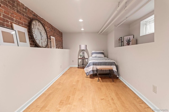 bedroom featuring brick wall and light wood-type flooring