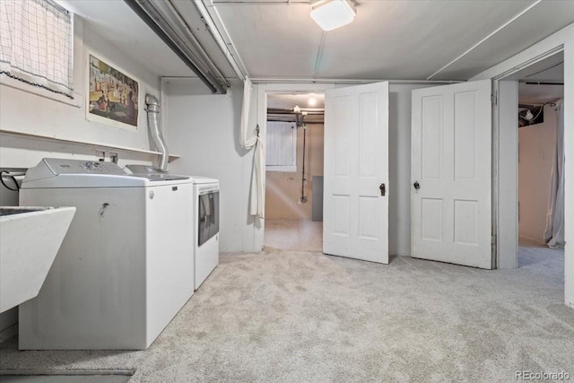 clothes washing area featuring light carpet, sink, and washer and dryer