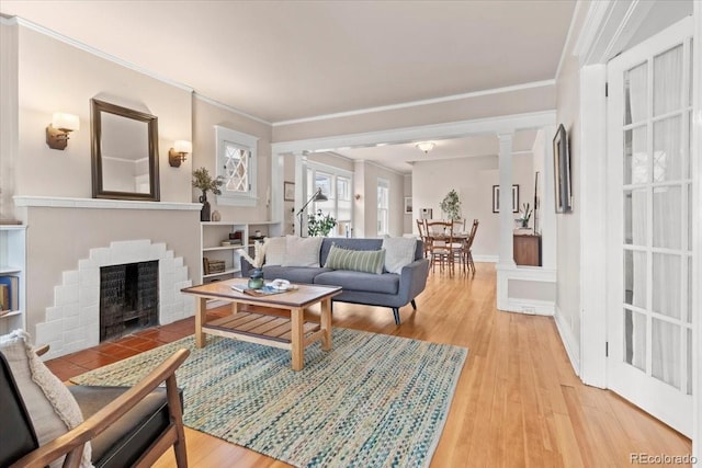 living room with light wood-type flooring, a fireplace, and ornamental molding