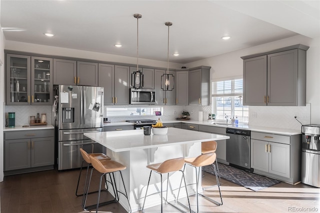 kitchen featuring appliances with stainless steel finishes, tasteful backsplash, hanging light fixtures, sink, and a kitchen island