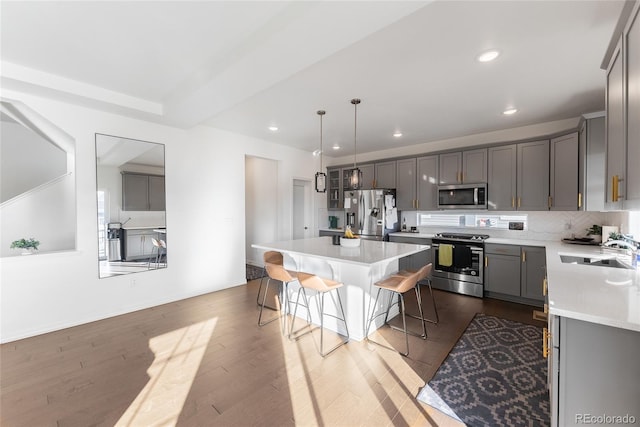 kitchen with a center island, a kitchen bar, appliances with stainless steel finishes, sink, and decorative light fixtures