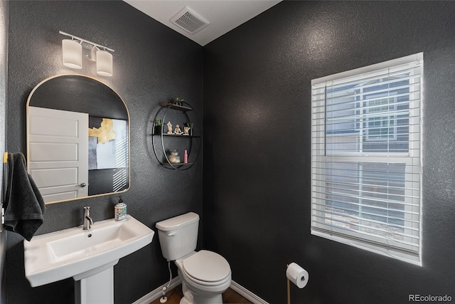 bathroom with sink, toilet, and a wealth of natural light