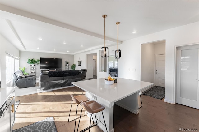 kitchen with a kitchen island, dark hardwood / wood-style floors, a kitchen bar, and pendant lighting