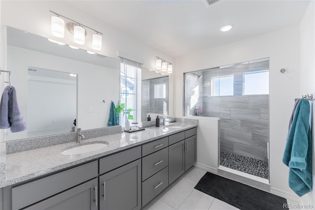 bathroom with a tile shower, tile patterned flooring, and vanity