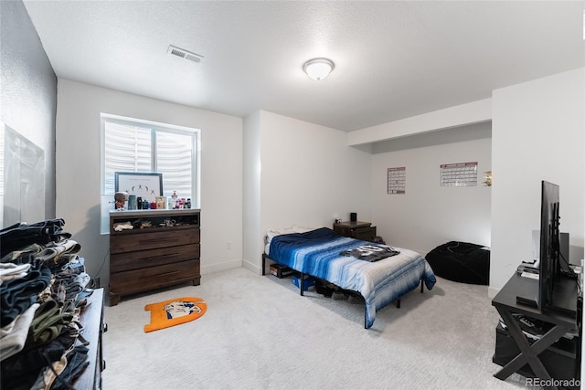 bedroom with a textured ceiling and light colored carpet