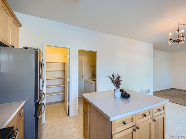 kitchen with light brown cabinetry, fridge with ice dispenser, a center island, pendant lighting, and independent washer and dryer