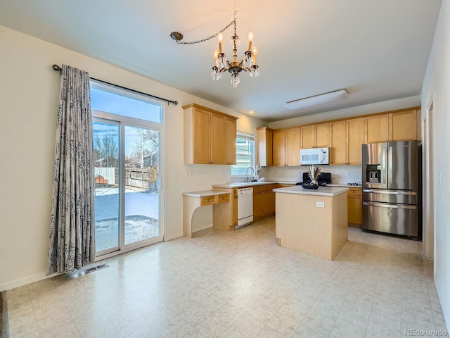 kitchen with sink, white appliances, hanging light fixtures, a center island, and light brown cabinets