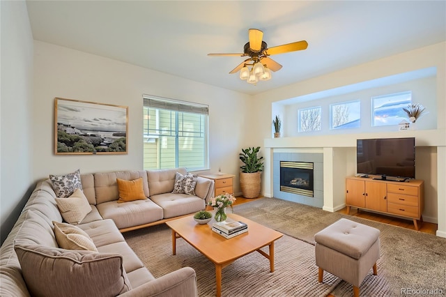 carpeted living room with a tile fireplace and ceiling fan