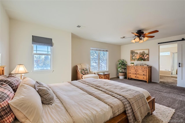 carpeted bedroom with a barn door and ceiling fan