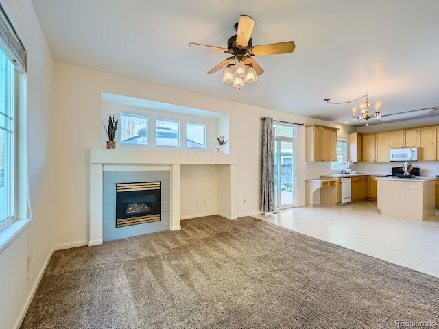 unfurnished living room with sink, carpet floors, ceiling fan with notable chandelier, and a fireplace