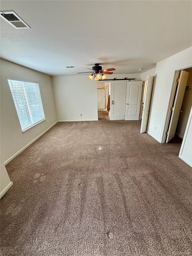 interior space featuring ceiling fan and a barn door