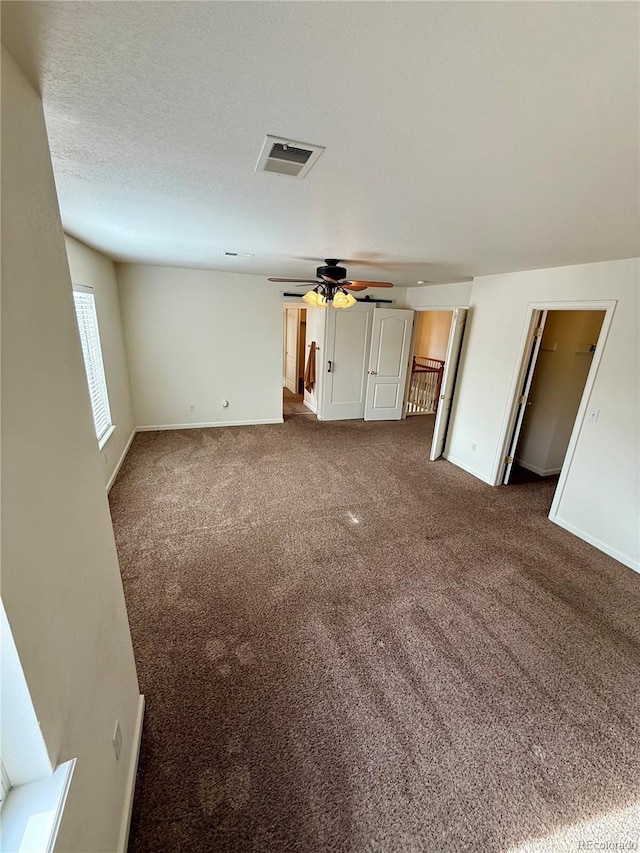 unfurnished living room featuring ceiling fan, carpet, and a textured ceiling