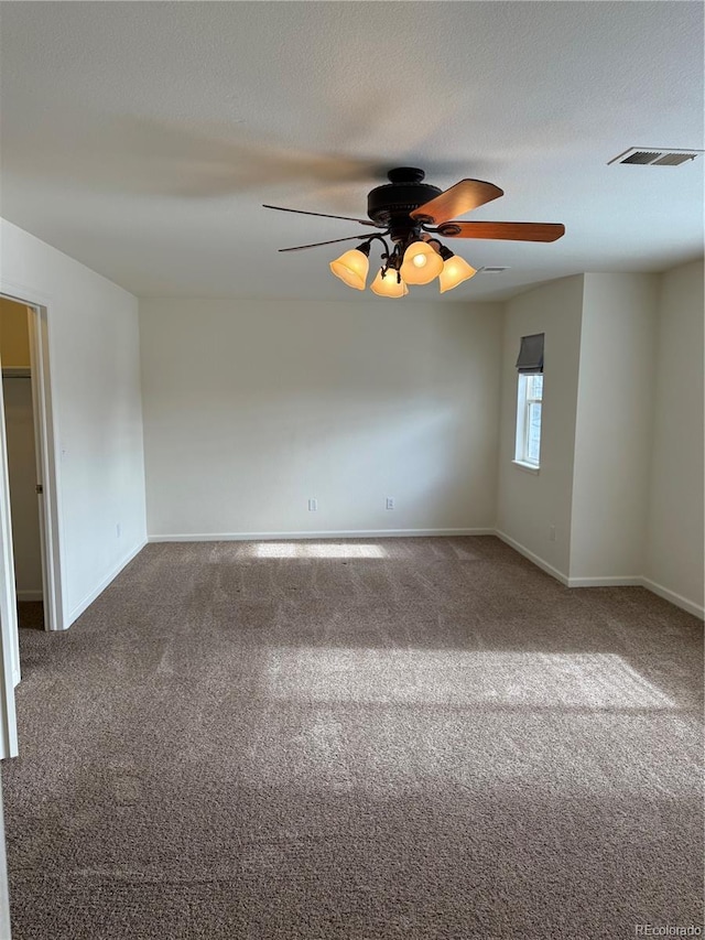 spare room featuring ceiling fan, carpet, and a textured ceiling