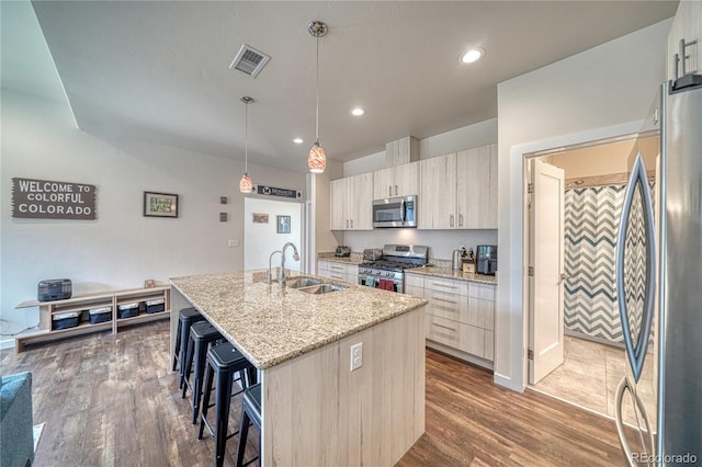728 Oak St Unit F, Salida, CO 81201 - kitchen featuring appliances with stainless steel finishes, a sink, a kitchen bar, a kitchen island with sink, and dark wood-style flooring