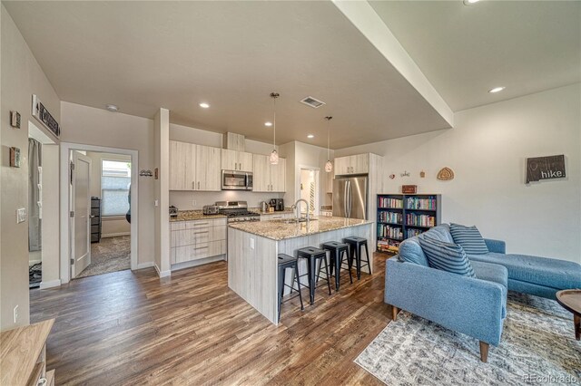 728 Oak St Unit F, Salida, CO 81201 - kitchen with appliances with stainless steel finishes, a sink, a breakfast bar area, dark wood-style flooring, and open floor plan