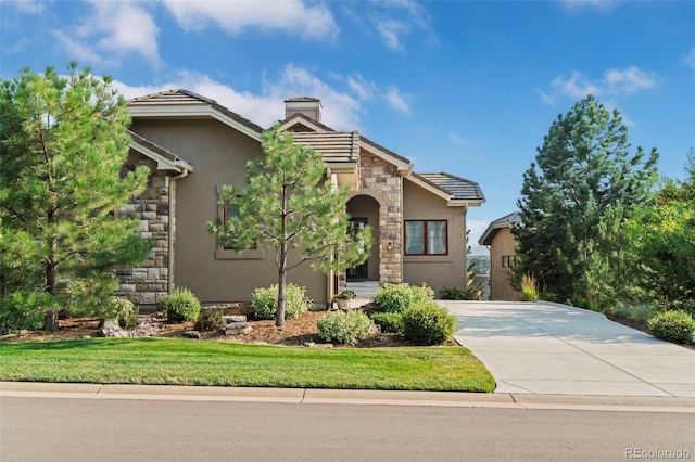 view of front of property with a chimney, a tile roof, stone siding, and stucco siding