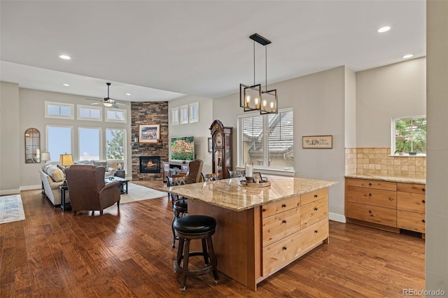 kitchen with ceiling fan with notable chandelier, a fireplace, dark wood finished floors, tasteful backsplash, and recessed lighting