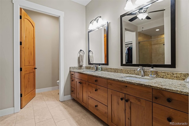 bathroom with a stall shower, a sink, a ceiling fan, and baseboards