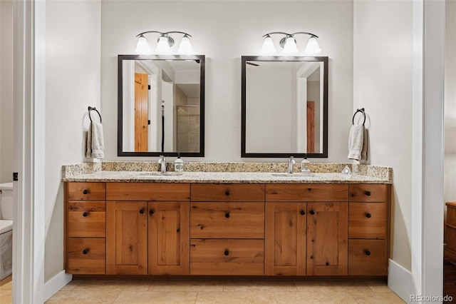 full bath with double vanity, baseboards, a sink, and toilet