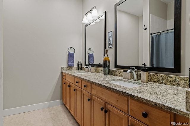 full bath with tile patterned flooring, double vanity, baseboards, and a sink