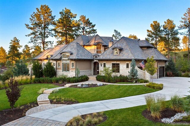 french country style house featuring a garage and a front lawn