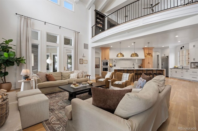 living room with sink, light hardwood / wood-style flooring, and a high ceiling