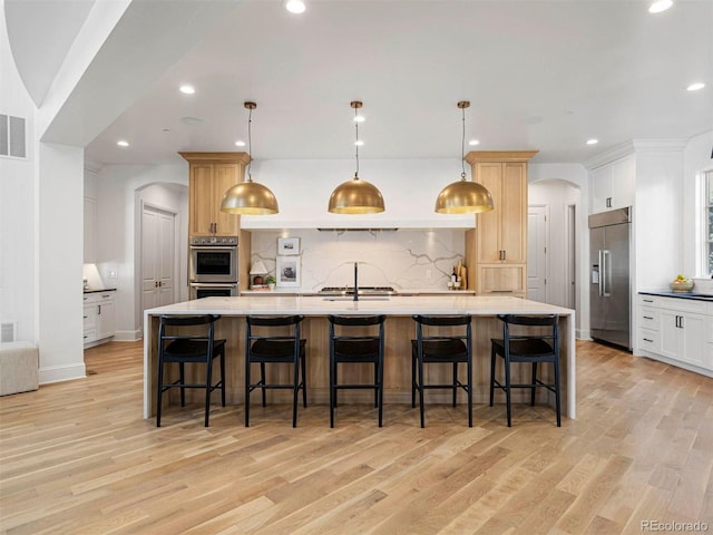 kitchen featuring pendant lighting, stainless steel appliances, and a large island with sink