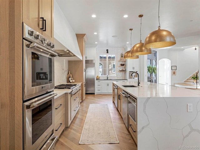 kitchen featuring sink, light stone countertops, hanging light fixtures, and white cabinets