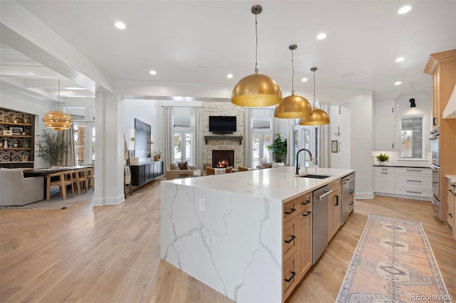 kitchen featuring pendant lighting, sink, light stone counters, stainless steel appliances, and a spacious island