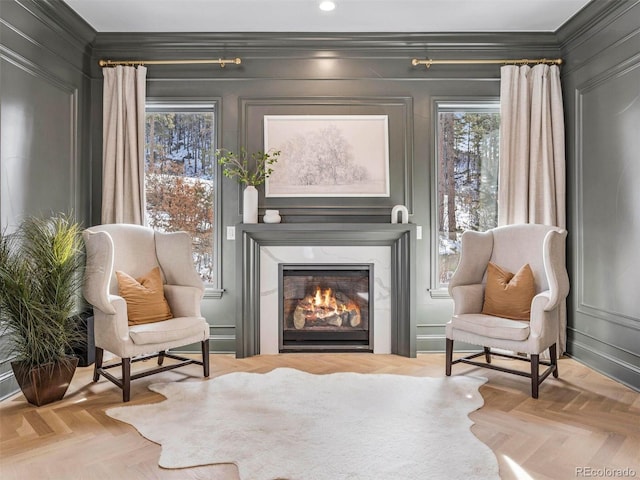 living area featuring light parquet flooring, a wealth of natural light, and crown molding