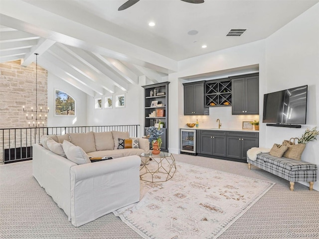 carpeted living room featuring wine cooler, ceiling fan with notable chandelier, lofted ceiling with beams, and indoor wet bar