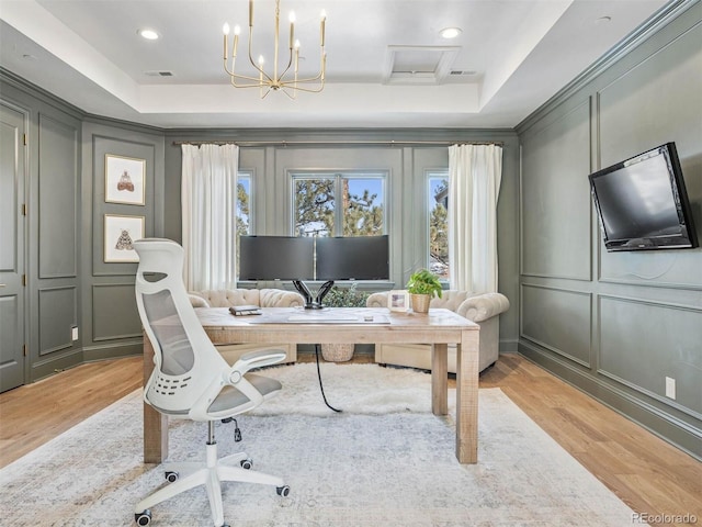 office area featuring ornamental molding, a tray ceiling, and light hardwood / wood-style flooring