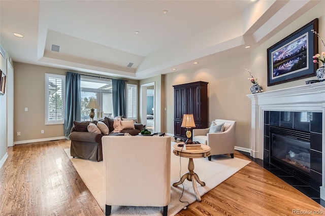 32 Silver Fox Cir, Greenwood Village, CO 80121 - living room featuring a tray ceiling, a tiled fireplace, wood finished floors, baseboards, and recessed lighting