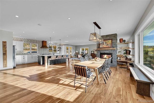 dining space featuring a fireplace, plenty of natural light, and light wood-type flooring