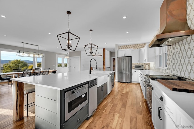 kitchen featuring white cabinetry, custom range hood, stainless steel appliances, and a large island with sink