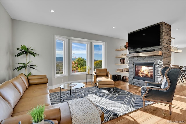 living room with light hardwood / wood-style floors and a stone fireplace