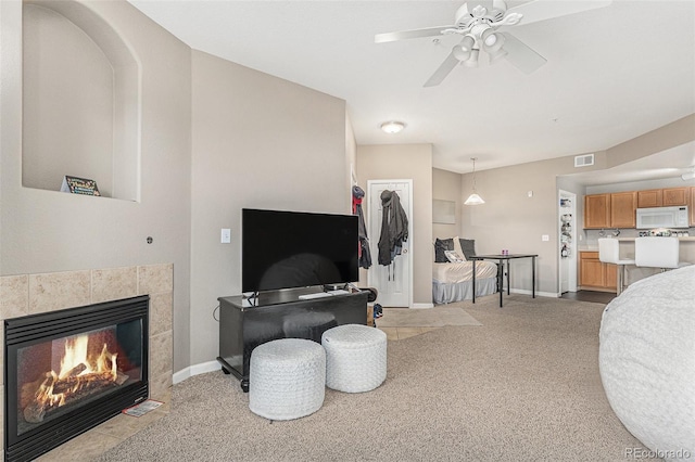 living area featuring visible vents, light carpet, a ceiling fan, a fireplace, and baseboards