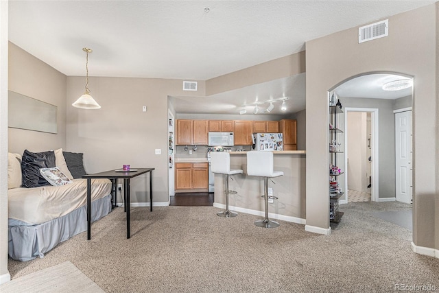 kitchen with white microwave, visible vents, refrigerator, arched walkways, and carpet flooring