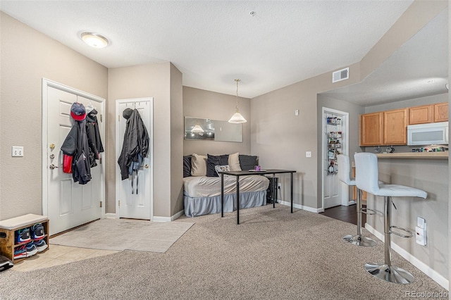 entrance foyer featuring visible vents, a textured ceiling, baseboards, and carpet floors