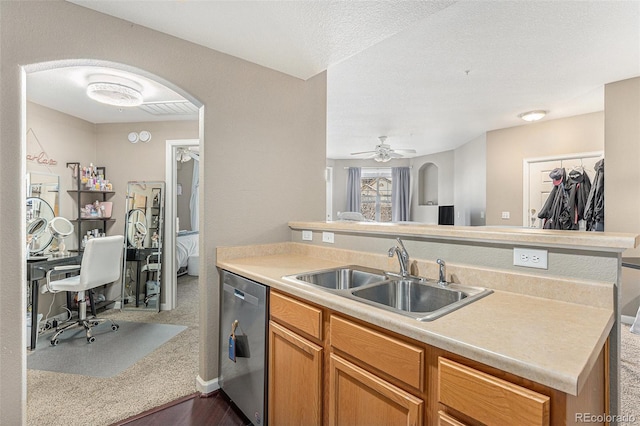 kitchen featuring arched walkways, dishwasher, light countertops, and a sink