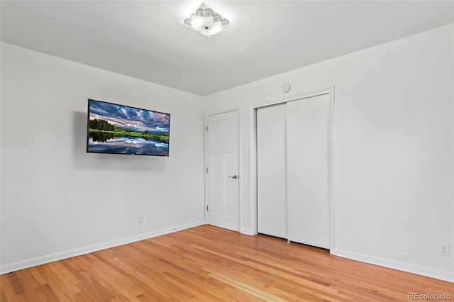 unfurnished bedroom with light wood-type flooring and a closet