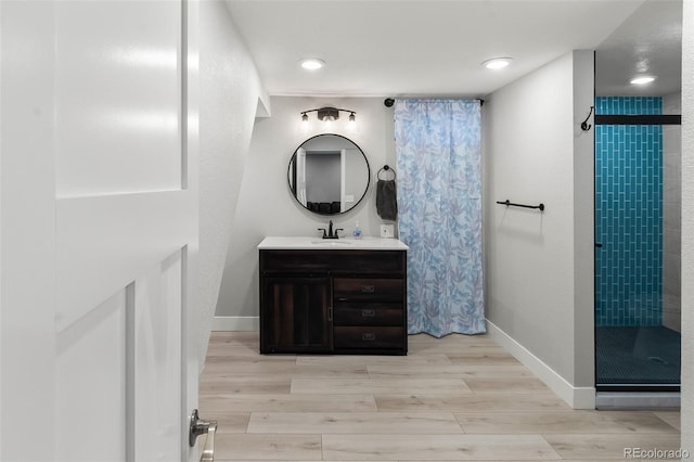 bathroom with tiled shower, wood-type flooring, and vanity