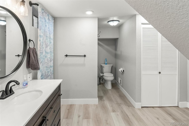 bathroom with hardwood / wood-style flooring, vanity, and toilet