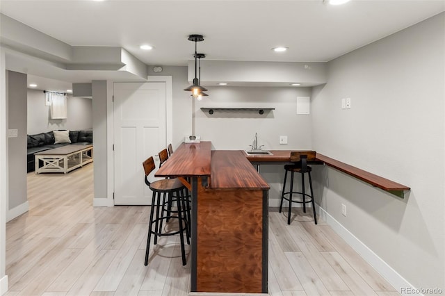 kitchen featuring wood counters, light wood-type flooring, a breakfast bar, and kitchen peninsula