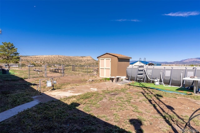 view of yard featuring an outbuilding, a mountain view, fence, and a shed