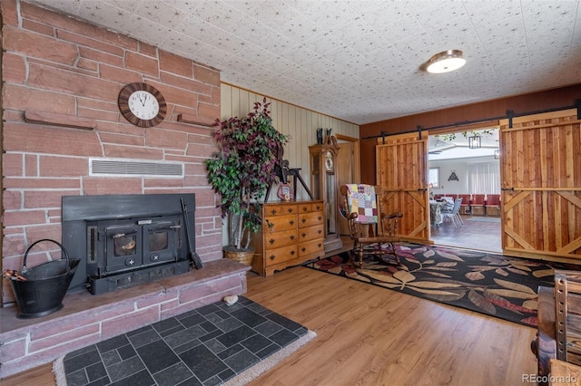 living room with a barn door, visible vents, and wood finished floors