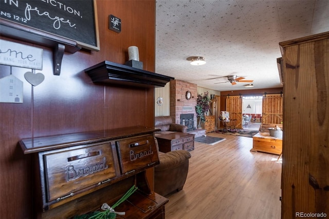 living room featuring a fireplace, ceiling fan, and wood finished floors